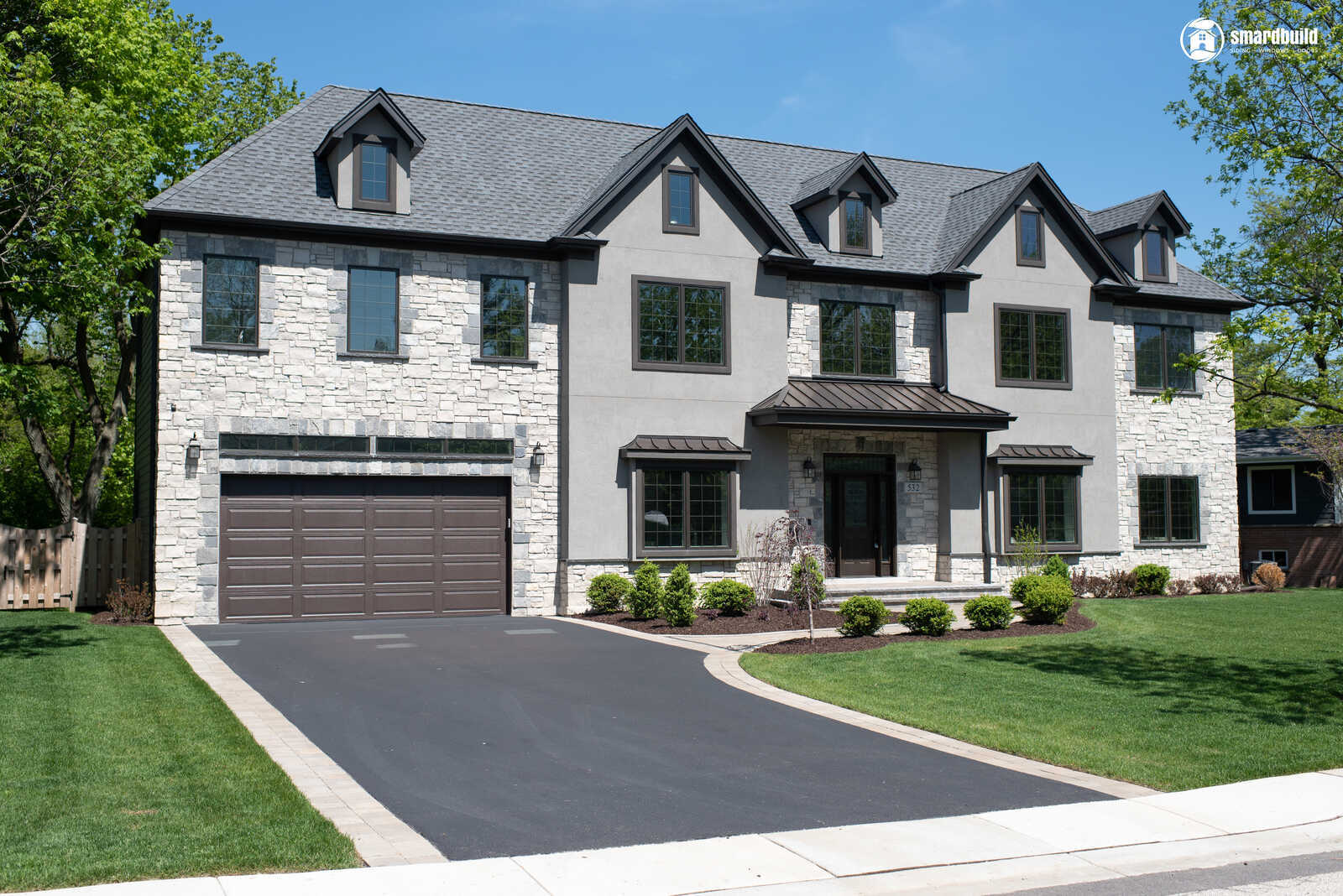 A modern stone house with a black roof and well-maintained front yard by Smardbuild in Naperville, Chicago